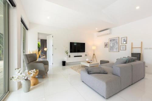 a living room with a couch and a tv at Villa White Orchid in Choeng Mon Beach