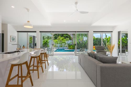 an open kitchen and living room with a couch and chairs at Villa White Orchid in Choeng Mon Beach