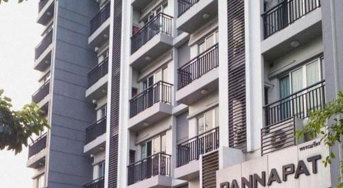 a tall building with balconies and a sign on it at Pannapat Place in Bangkok