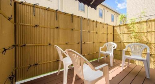 three white chairs sitting on a deck with a fence at La'gent Inn Kesennuma in Higashi-hachimammae