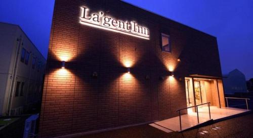 a brick building with a neon sign on it at La'gent Inn Kesennuma in Higashi-hachimammae