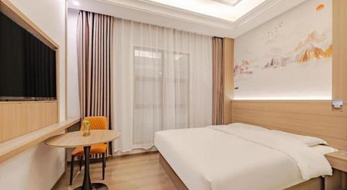 a bedroom with a bed and a table and a window at GreenTree Alliance Anhui Hefei South Passenger Station South High Speed Railway Station Hotel in Hefei