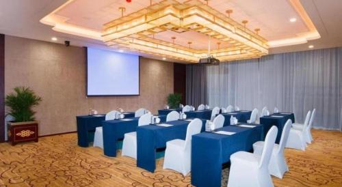 a room with blue tables and white chairs and a screen at New Century Grand Hotel Xi'an Xizang Building in Xi'an
