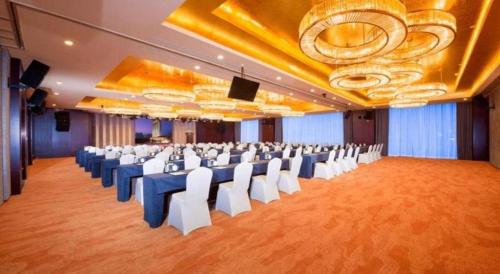 a large banquet hall with white chairs and a stage at New Century Grand Hotel Xi'an Xizang Building in Xi'an