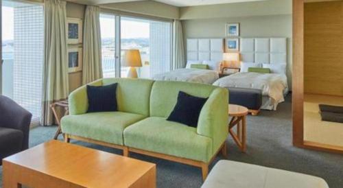 a hotel room with a green couch and a bed at Hotel Harvest Nankitanabe in Tanabe