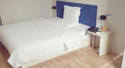 a large white bed with a blue headboard and a table at 7 Days Inn Changzhou Yancheng Technology Metro Station in Changzhou