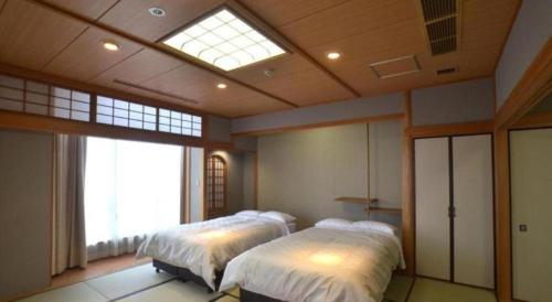 a bedroom with two beds and a skylight at Hamakan Hotel in Unzen