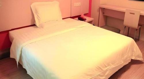 a white bed in a room with a desk at 7 Days Inn Changchun Zhengyang Street Changchun Park Branch in Changchun