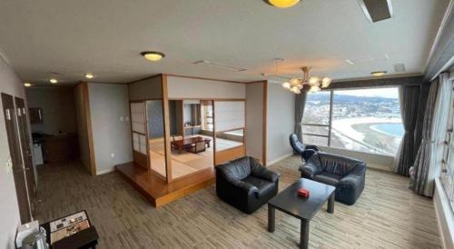 a living room with leather furniture and a large window at Hotel AreaOne Banjinmisaki in Kashiwazaki