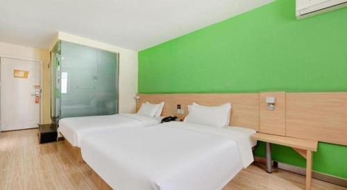 a large white bed in a room with a green wall at 7 Days Inn West Gate of Taiyuan University of Technology in Taiyuan