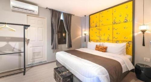 a bedroom with a large bed with a yellow headboard at Rueangrat Hotel in Ranong
