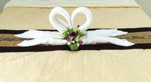 a pair of white gloves with a bouquet on a bed at Rueangrat Hotel in Ranong