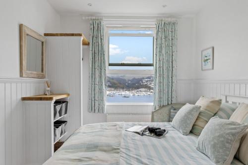 a bedroom with a bed and a large window at Kittiwake - Outstanding River Views in Dartmouth
