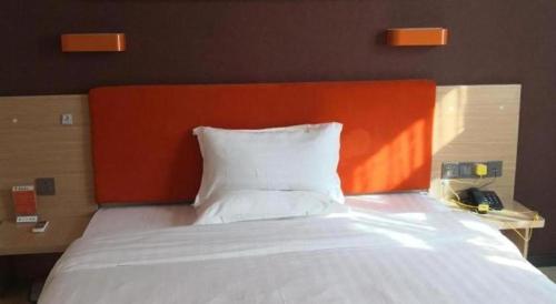 a bed with an orange headboard and a white pillow at 7 Days Premium Hotel Ji'an Taihe Gongnongbing Avenue in Ji'an