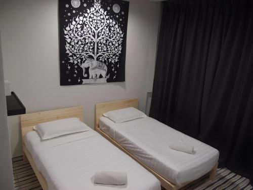 two beds in a room with a picture on the wall at De Chukai Hotel in Cukai