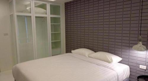 a bedroom with a white bed and a brick wall at Silom Studios in Bangkok