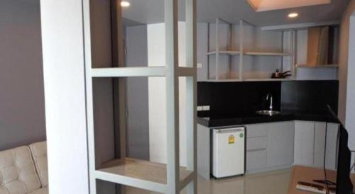 a kitchen with white cabinets and a white refrigerator at Silom Studios in Bangkok