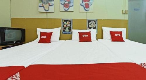 a large bed with red pillows and a tv at SPOT ON 90625 Super Green Grass Hotel in Yong Peng