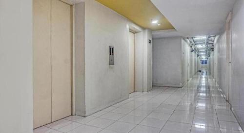 a hallway with white walls and white tile floors at Capital O 91820 S&a Collection 2 in Jakarta