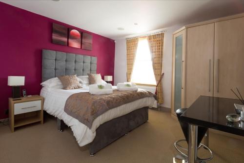 オックスフォードにあるCherwell Gates 4 Bed Luxury Oxford Apartment for 8 with Roof terraceの紫の壁のベッドルーム1室(大型ベッド1台付)