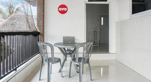 a table with two chairs and a laptop on a balcony at Hotel O Wisma Sidosari Syariah in Bandar Lampung