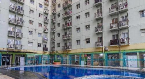 a large building with a swimming pool in front of it at OYO 94150 Gateway Apartment Pasteur By Eldian in Bandung