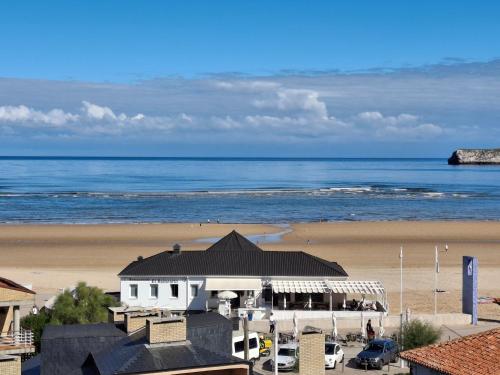 a view of a beach with a building and the ocean at Doña Carmen Playa Boutique in Suances