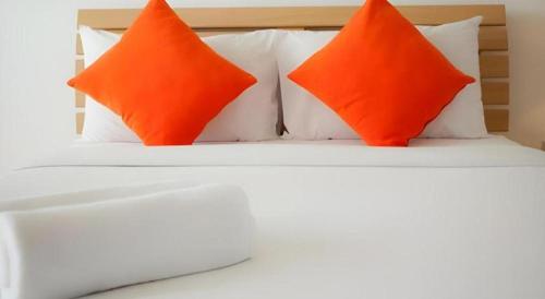 two orange pillows sitting on top of a white bed at Meesuk ChiangRai Hotel in Chiang Rai