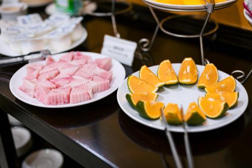 two plates of food on a counter with oranges andcakes at Gardenia Hue Hotel in Hue