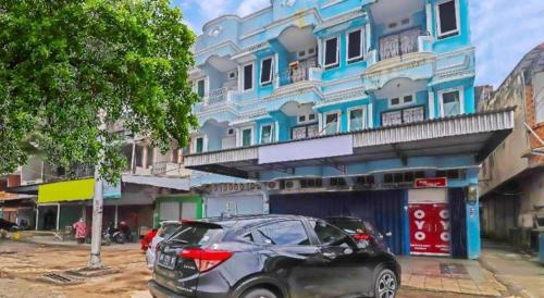 a car parked in front of a blue building at Hotel O Benteng Kost in Jambi
