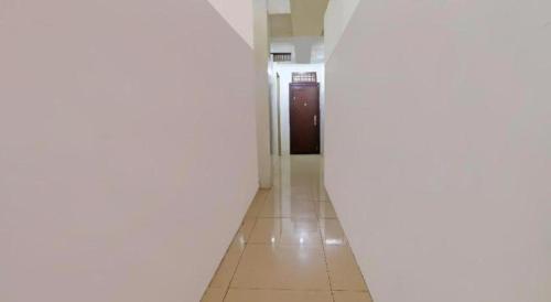 a long hallway with a door and a tile floor at Hotel O Benteng Kost in Jambi