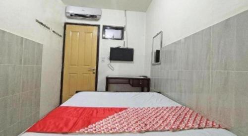 a bedroom with a bed with a red blanket at Hotel O Benteng Kost in Jambi
