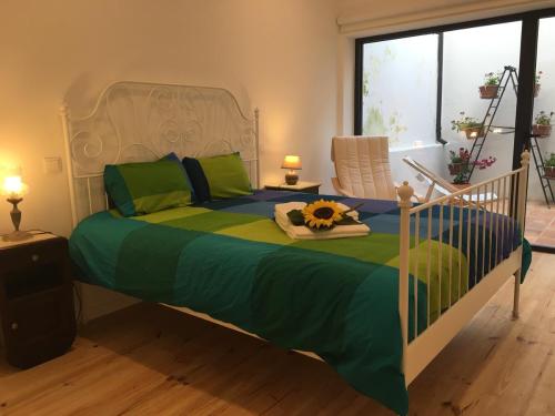 a bedroom with a bed with a green and blue comforter at Casa dos Pátios in Aveiro