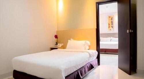 a bedroom with a white bed and a bathroom at Life Hotel Soekarno Hatta Makassar in Makassar