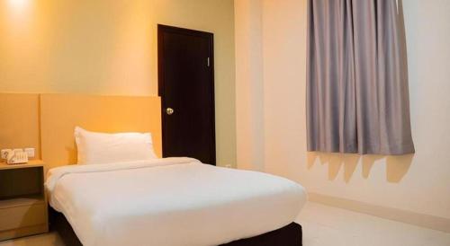 a bedroom with a white bed and a black door at Life Hotel Soekarno Hatta Makassar in Makassar