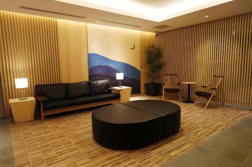 a living room with a black couch and a table at KEIKYU EX INN Tokyo Nihombashi in Tokyo