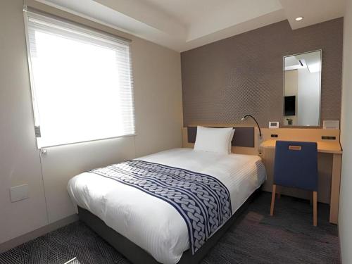 a bedroom with a bed and a desk and a window at KEIKYU EX INN Tokyo Nihombashi in Tokyo