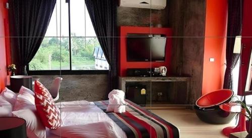 a bedroom with a bed with red walls and a tv at The B Ranong Trend Hotel in Ranong