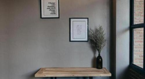 a table with a vase with a plant on a wall at Triple B sleep and relax in Nakhon Ratchasima