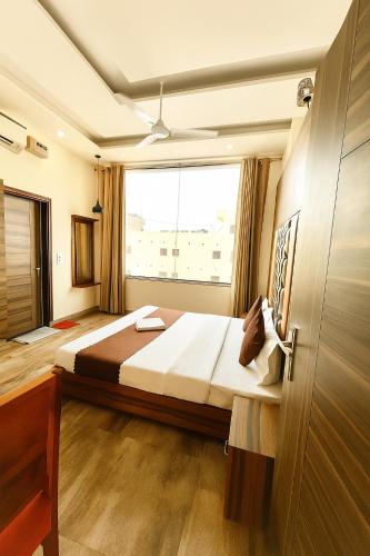 a bedroom with a large bed with a large window at Hotel Woodcrest by Sidham Group !! Comfortable and Peaceful Stay !! Top Rated !! Preferred Hotel Chain in Chandīgarh
