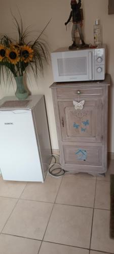 a dresser with a microwave and a vase of flowers at l'ancienne épicerie in Oradour-sur-Glane