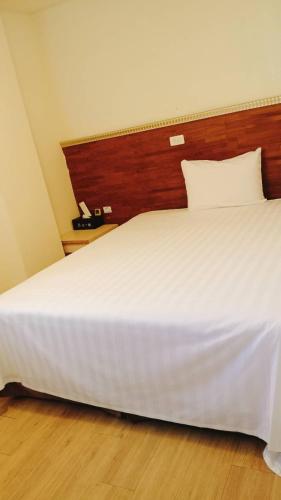 a large white bed with a wooden head board at 又一宿-又上的臨時客棧 in Taitung City