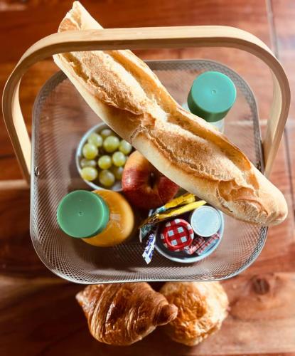 ein Korb mit Brot und Obst auf dem Tisch in der Unterkunft Airelles Spa - Jacuzzi - Sauna - Gîte de charme in Bucquoy