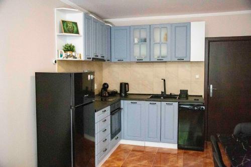 a kitchen with blue cabinets and a black refrigerator at Forest Dream Apartment - Elit Pamporovo in Pamporovo