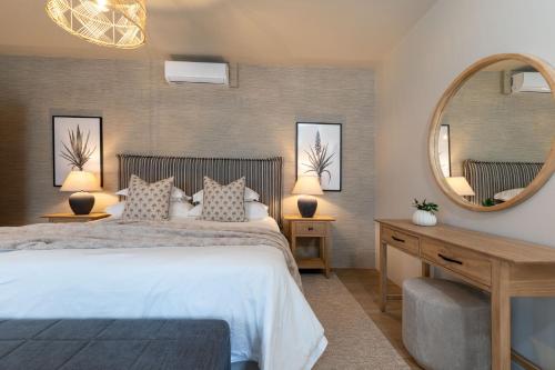 a bedroom with a large bed and a mirror at SEASENSE Boutique Beach Villa in Wilderness