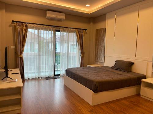 une chambre avec un lit et une grande fenêtre dans l'établissement The Lake Cozy 3BR Villa Pattaya, à Ban Huai Yai