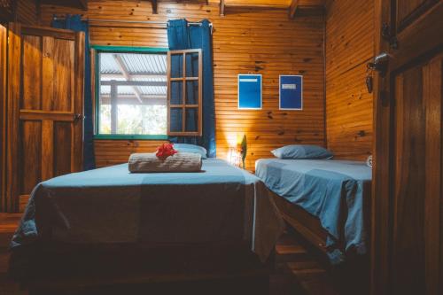 a bedroom with two beds in a wooden cabin at Casa Aldirica in Cahuita