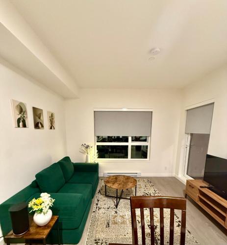 a living room with a green couch and a tv at Victoria Colwood Place in Colwood