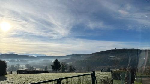 un campo con una valla y montañas al fondo en Chaintre La Vallée, en Château-Chinon