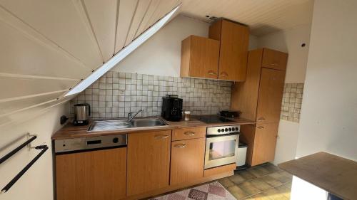 a small kitchen with a sink and a stove at Gemütliche Wohnung, Heimkino, Couch & Küche in Siegen